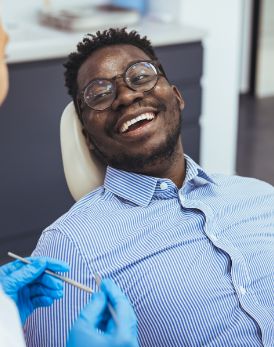 Man in the dental chair grinning at his dentist